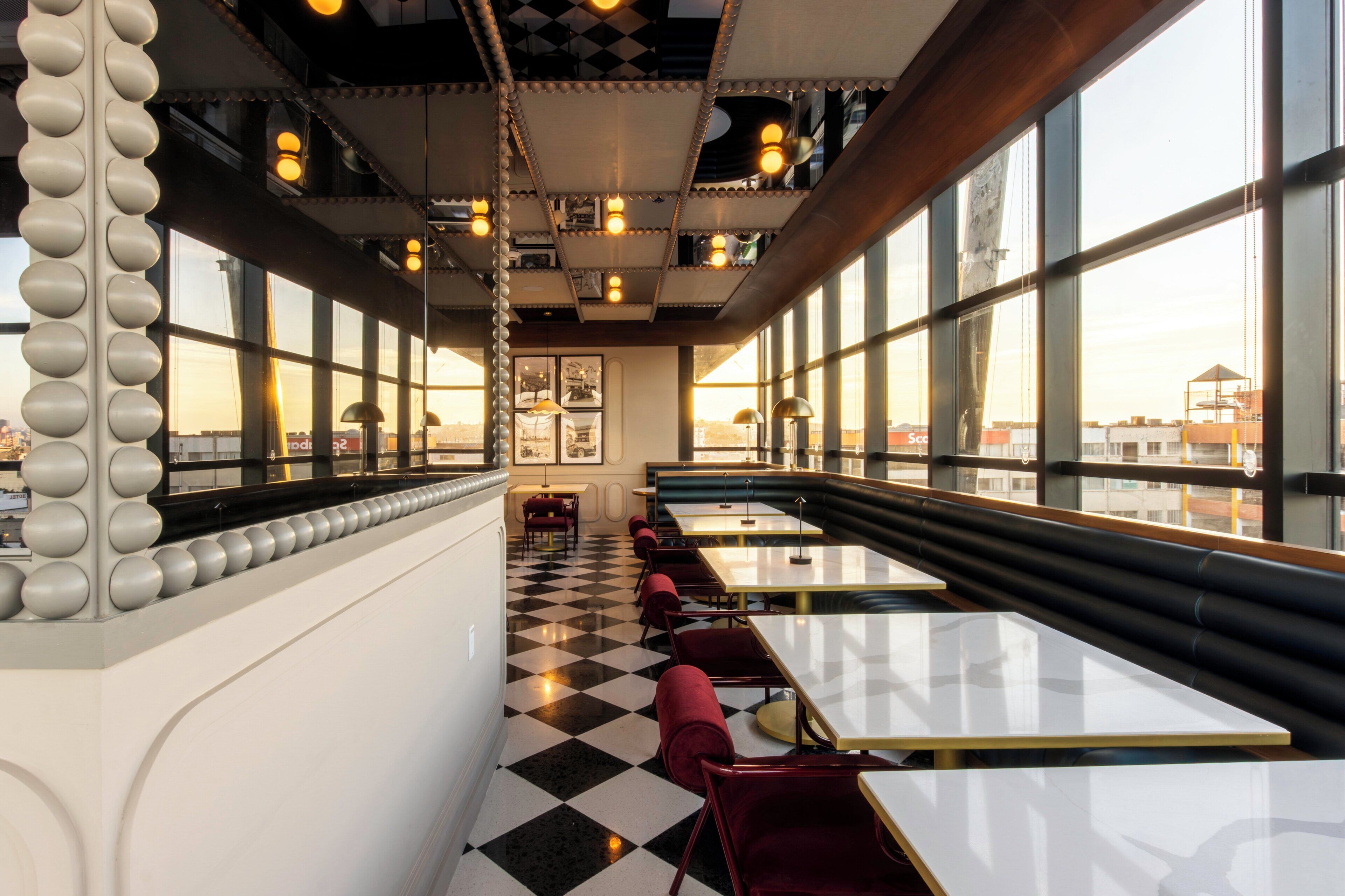 A restaurant with checkered flooring, red upholstered chairs, and tables.