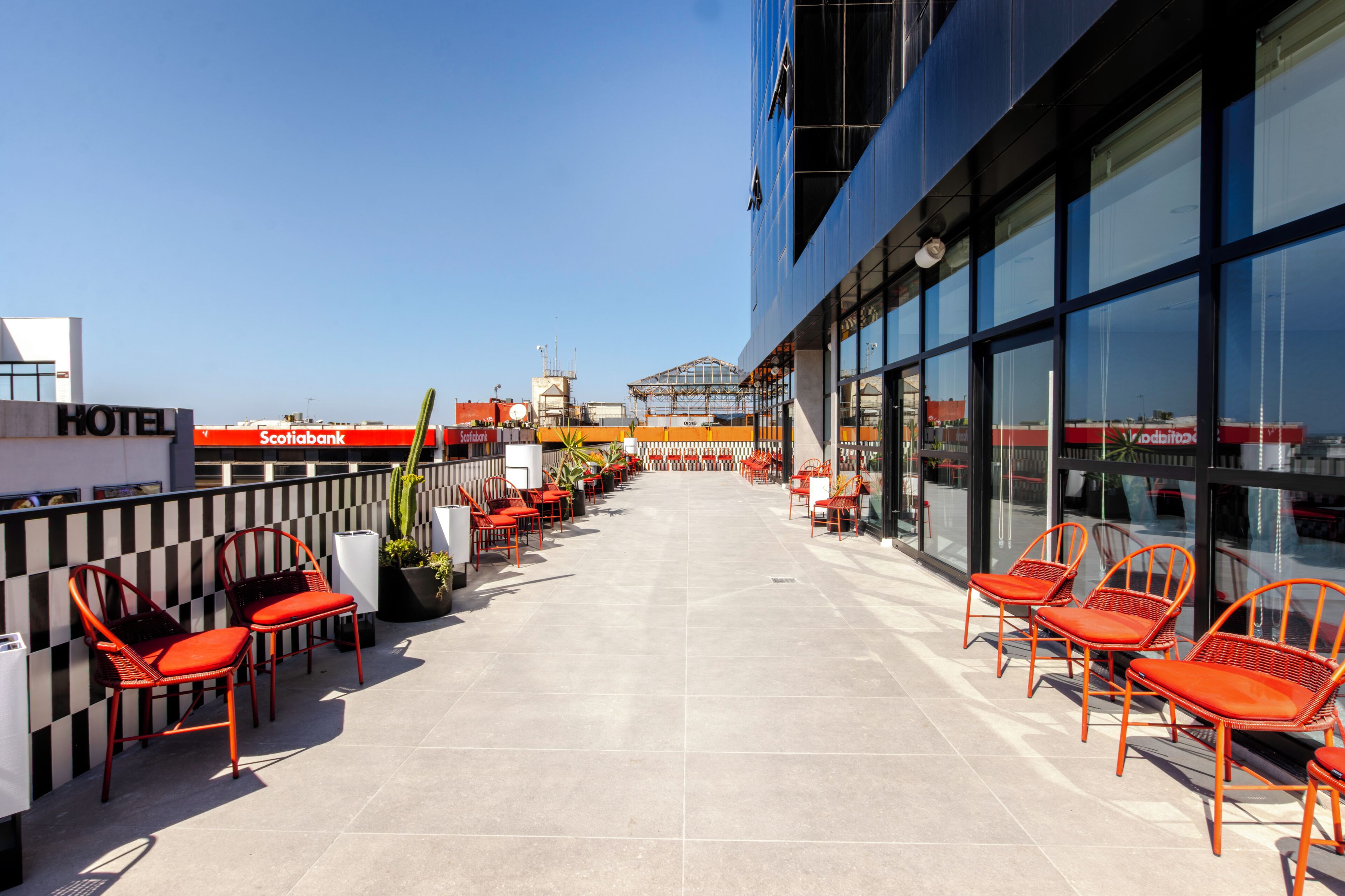 A hotel rooftop terrace with outdoor seating and a clear view of the city skyline.