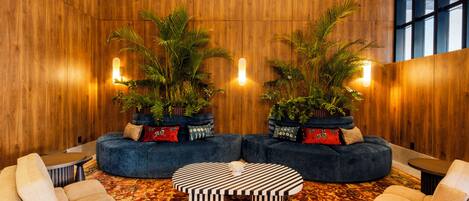 Un vestíbulo con pared de madera, dos sofás, una mesa de centro y plantas en macetas.