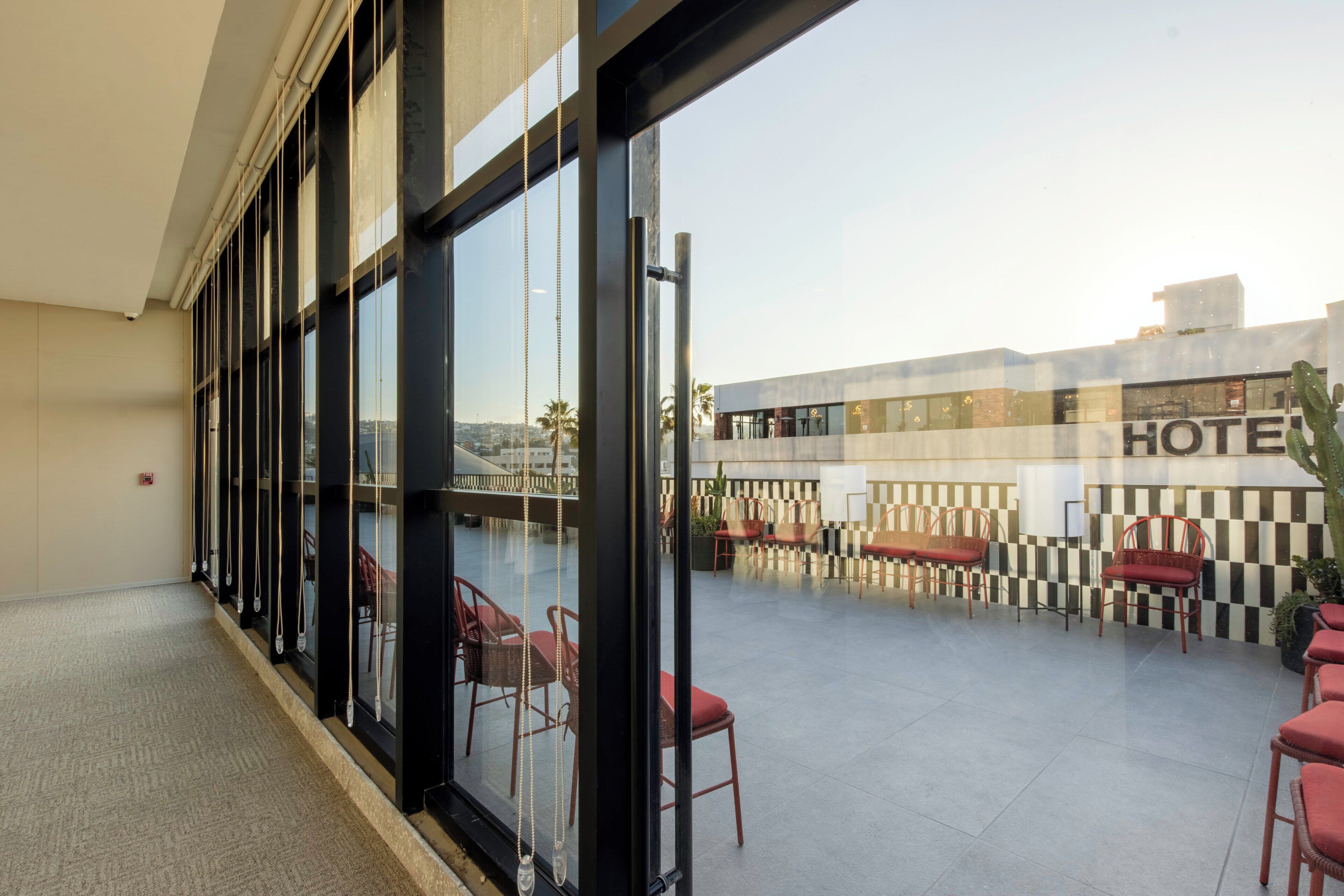 Une terrasse sur le toit d’un hôtel offrant une vue sur les toits de la ville, avec des sièges en plein air et un mur à motifs à carreaux.