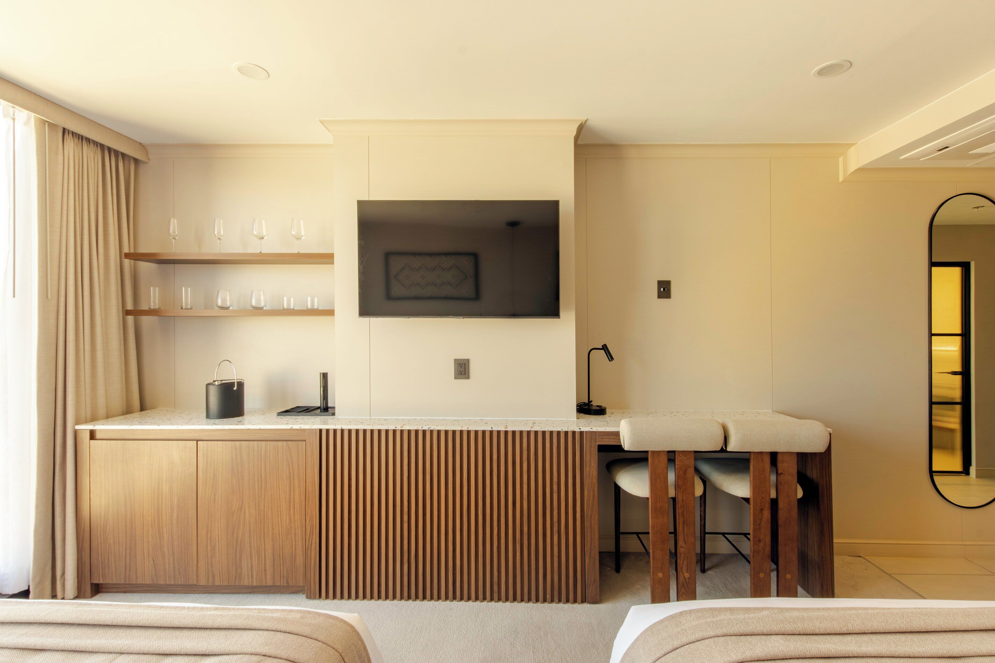 Una habitación de hotel moderna con kitchenette, una zona de comedor y un espejo grande.