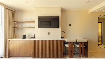 Una habitación de hotel moderna con kitchenette, una zona de comedor y un espejo grande.