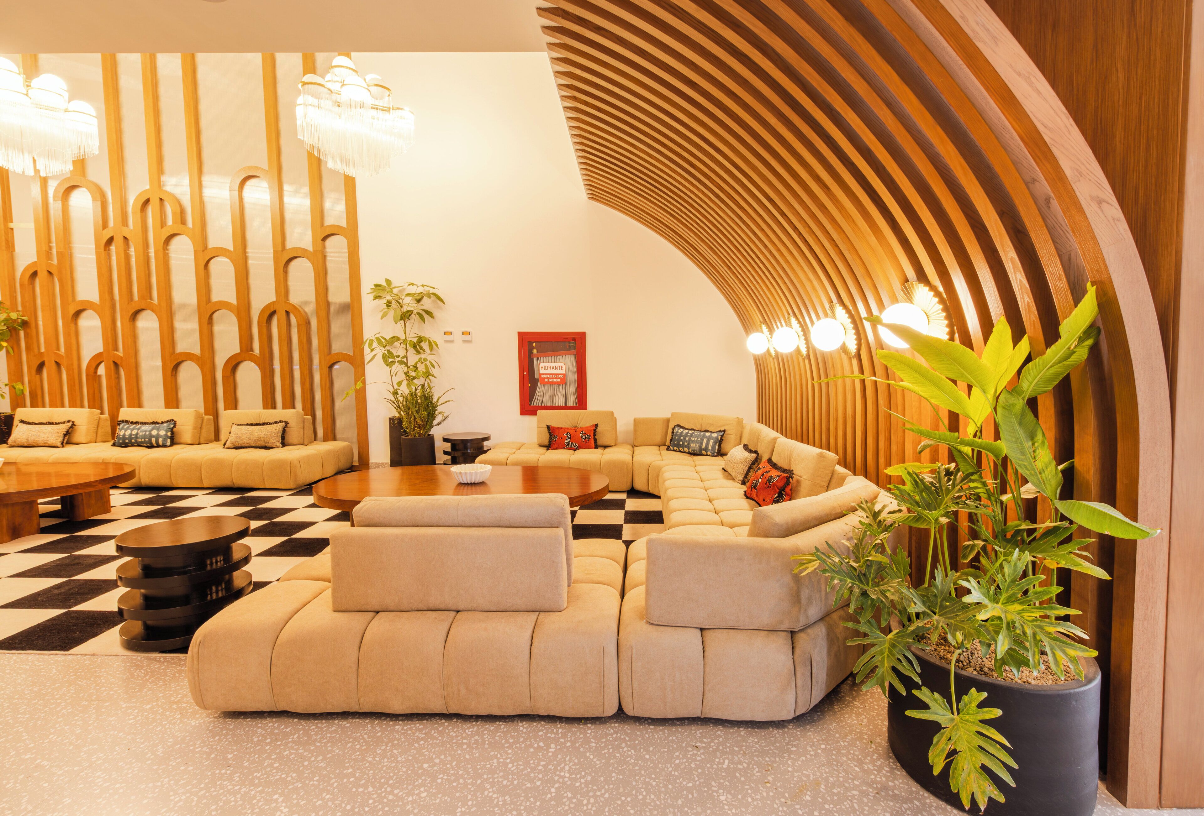 A modern lounge area with a checkered floor, a sectional sofa, a coffee table, and a potted plant.