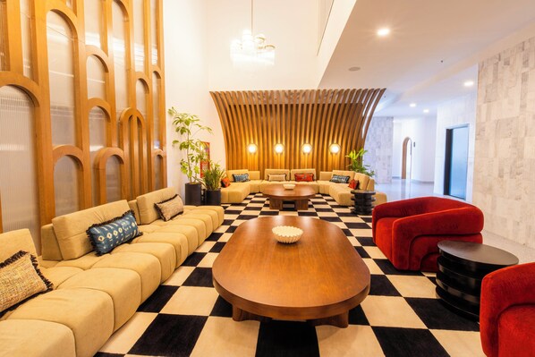 A modern lounge area with a checkered floor, a central wooden coffee table, and a seating arrangement that includes sofas and armchairs. - Hotel Indigo Tijuana Downtown by IHG (Tijuana)