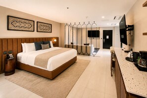A hotel room with a large bed, bedside tables, a desk with a coffee machine, a TV, and artwork on the walls. - Hotel Indigo Tijuana Downtown by IHG (Tijuana)
