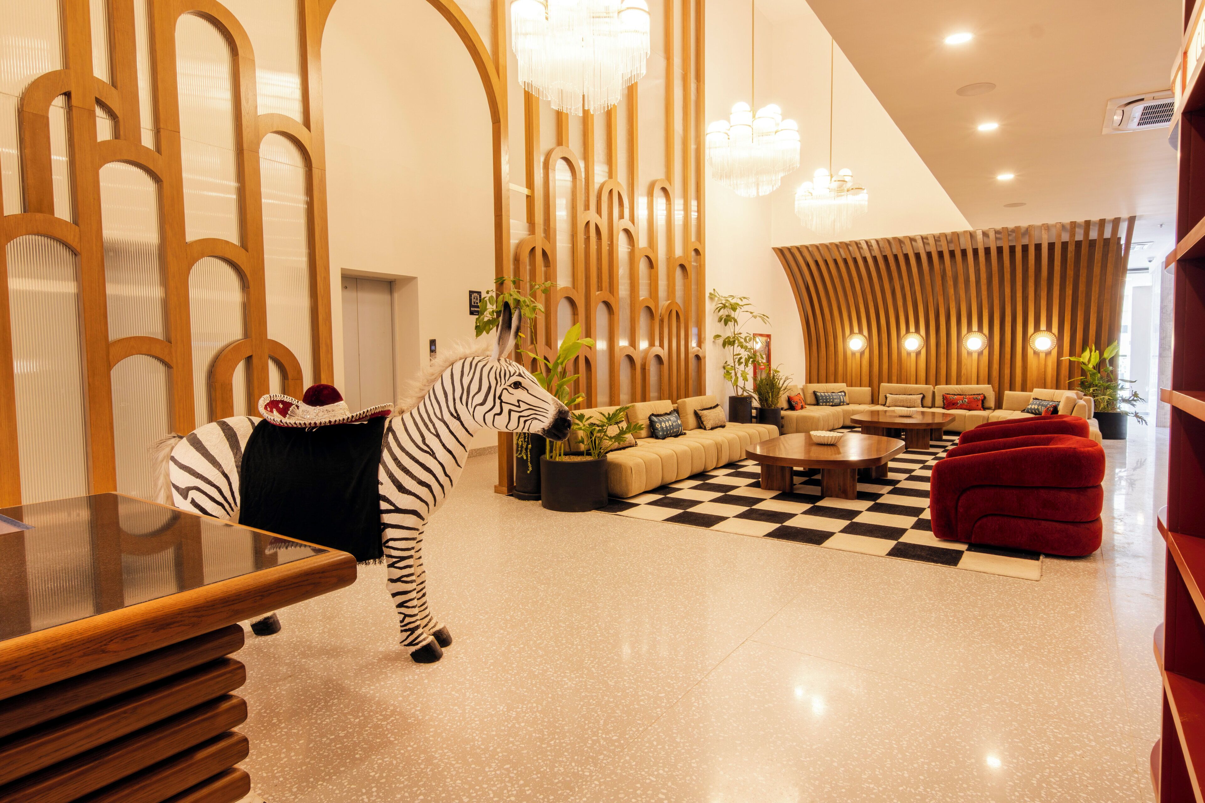 A modern interior with a zebra statue, a checkered floor, and a seating area with sofas and a red ottoman.