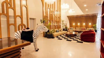 A modern interior with a zebra statue, a checkered floor, and a seating area with sofas and a red ottoman.