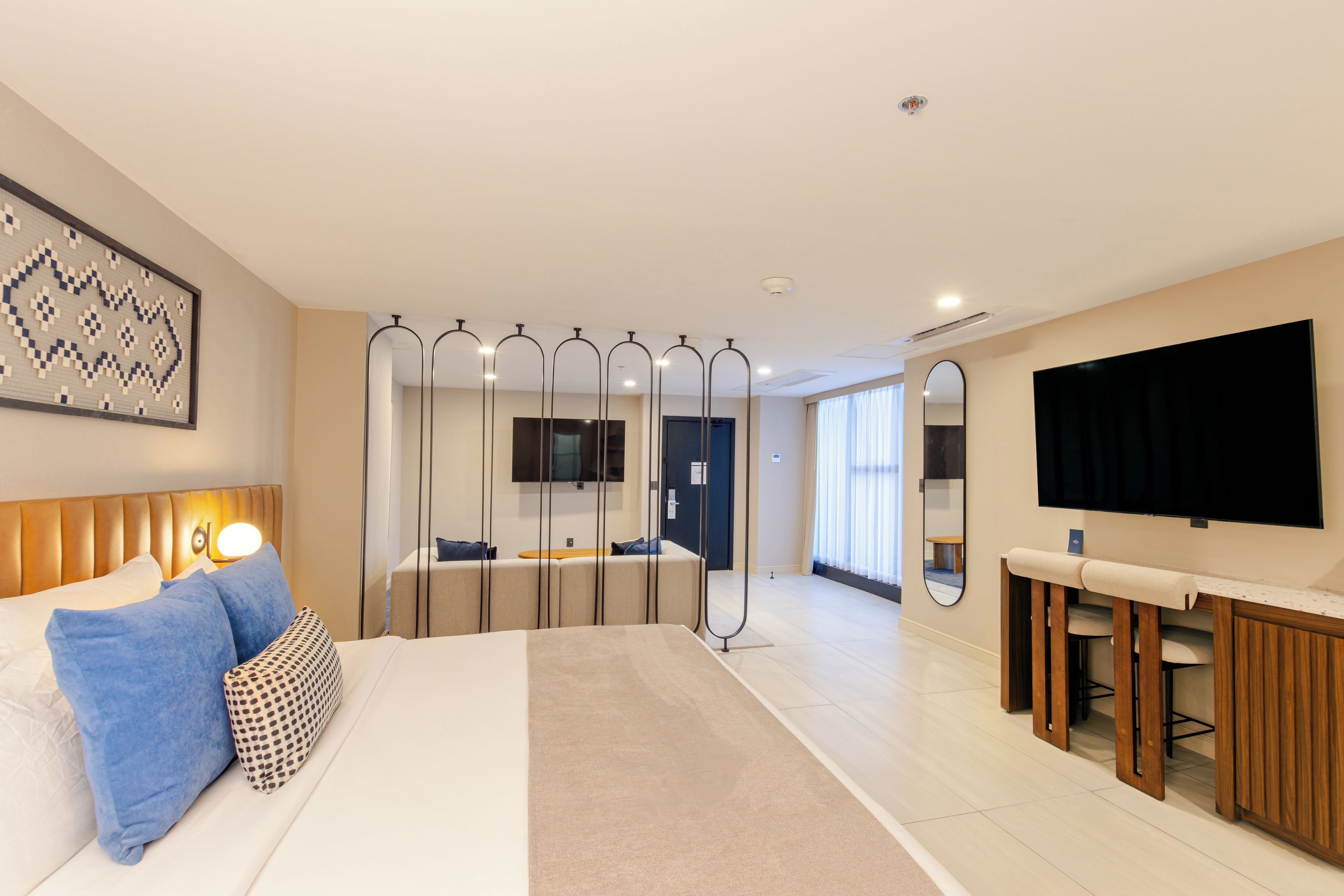 Una habitación de hotel con una cama, un escritorio, un televisor y un espejo.