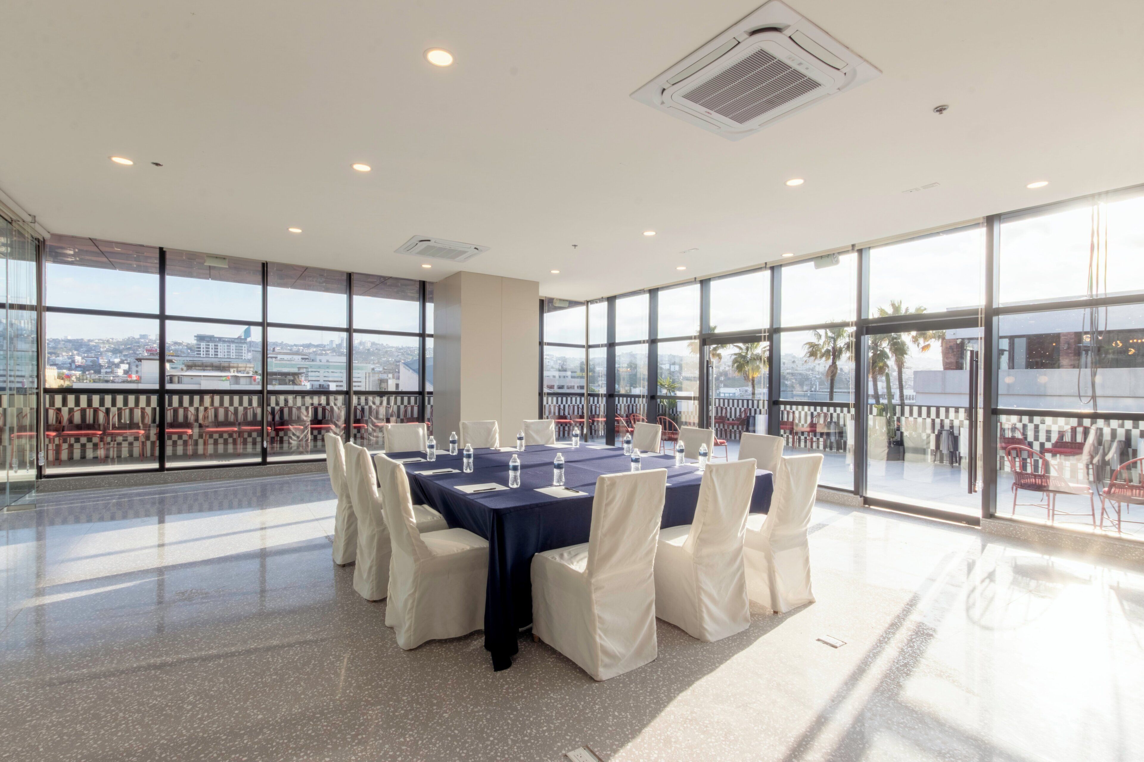 A conference room with a large table, chairs, and a city view through large windows.