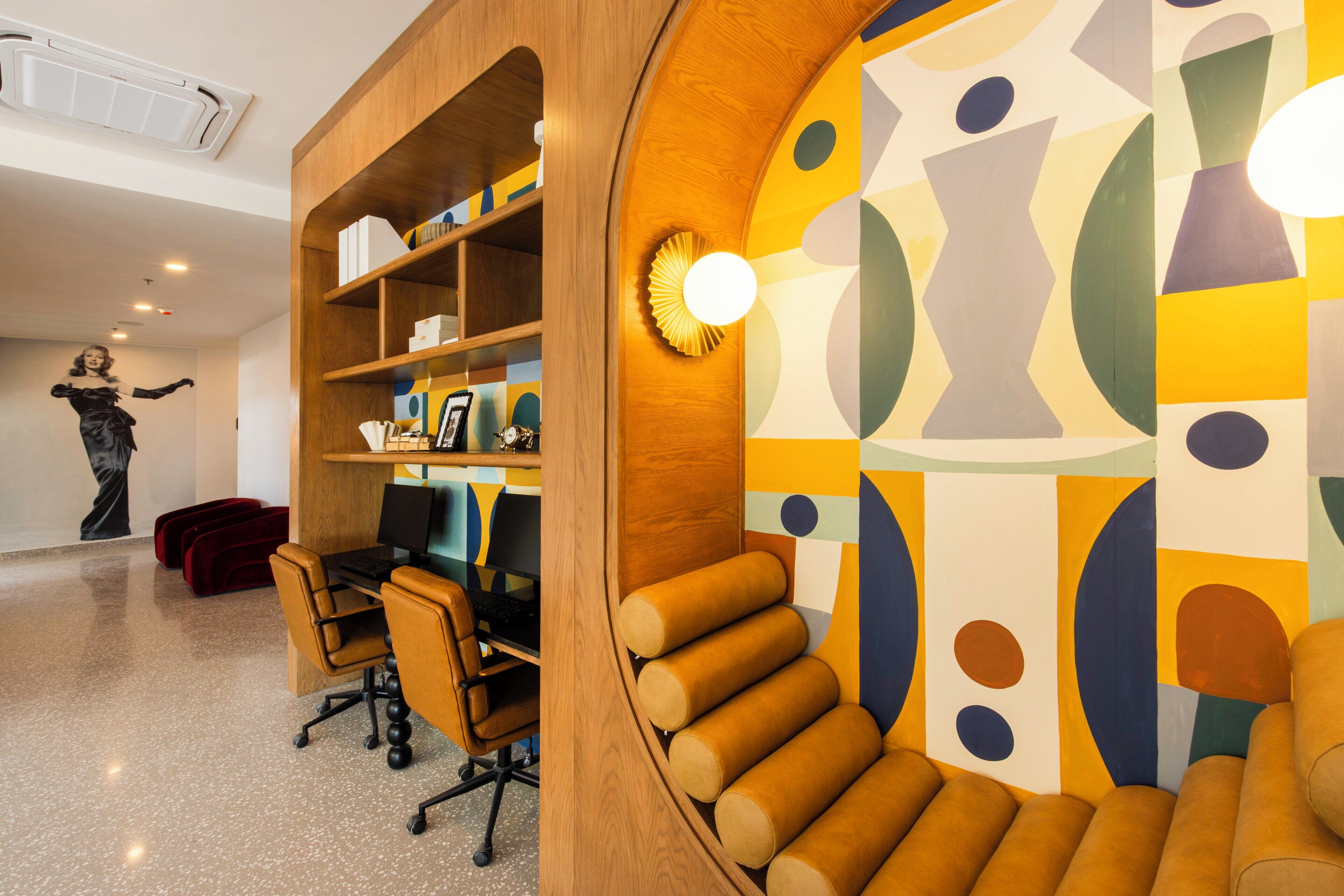 A modern office space with a curved wooden desk, a computer, and a bookshelf.