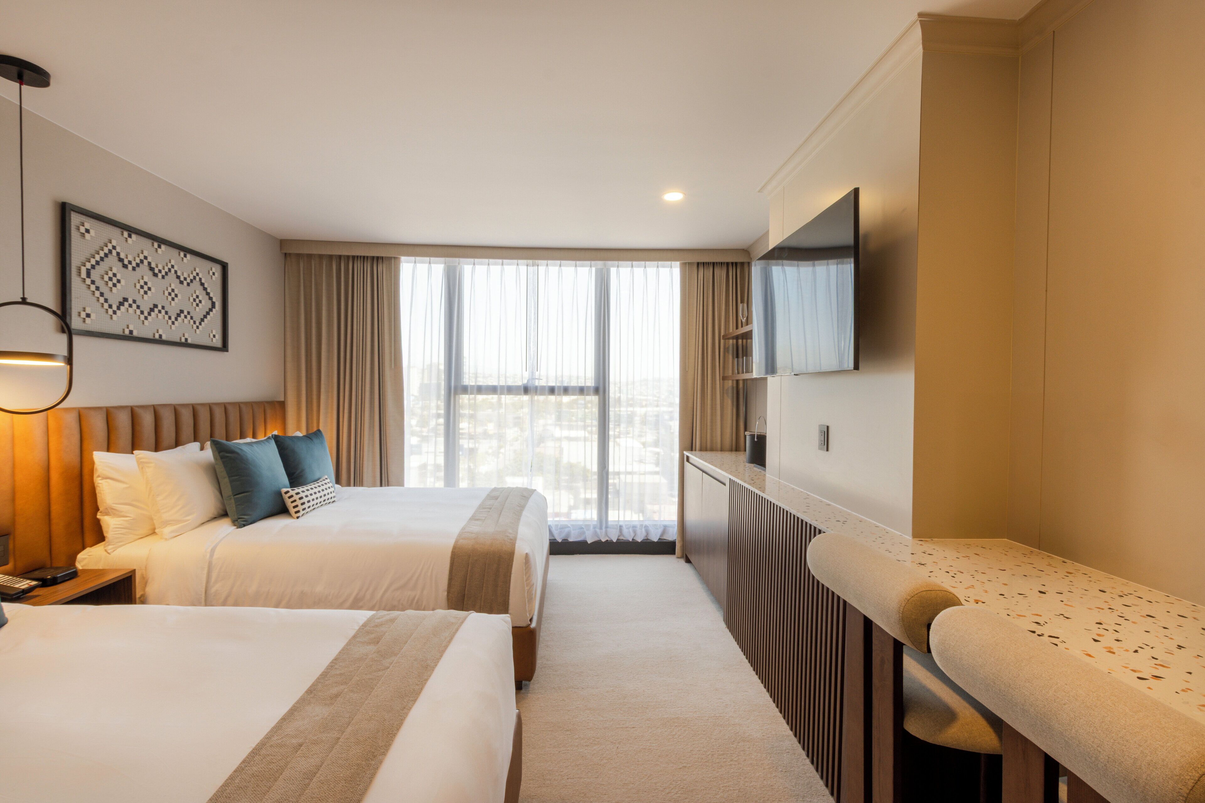 Une chambre d’hôtel avec deux lits, une télévision, un bureau et une fenêtre avec des rideaux.