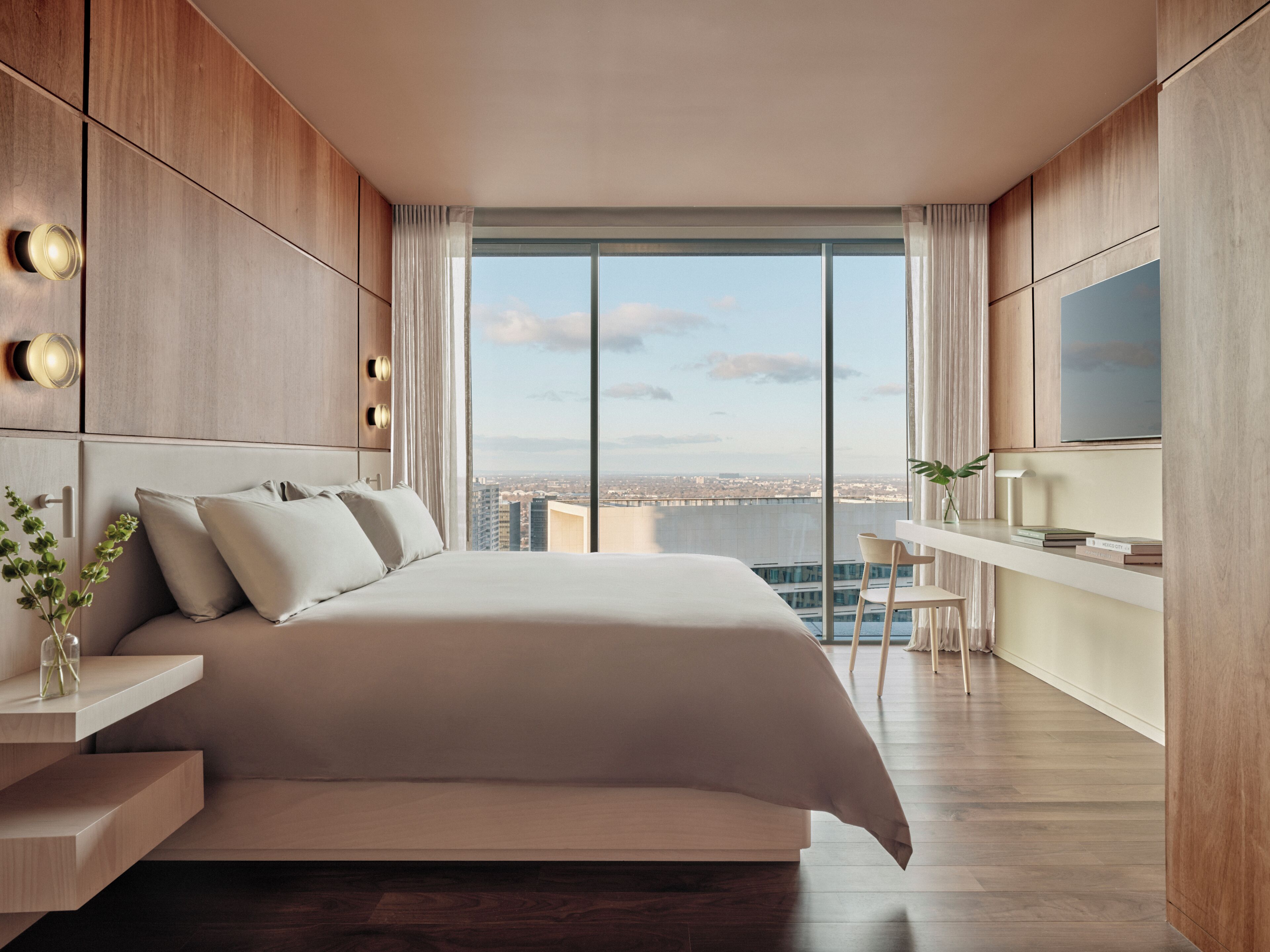 Un dormitorio moderno con una cama grande, un escritorio, una silla y un televisor.