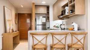 A kitchen with a central island, wooden chairs, a refrigerator, and a microwave. - kery’s sweet home in valle nevado (Lo Barnechea)