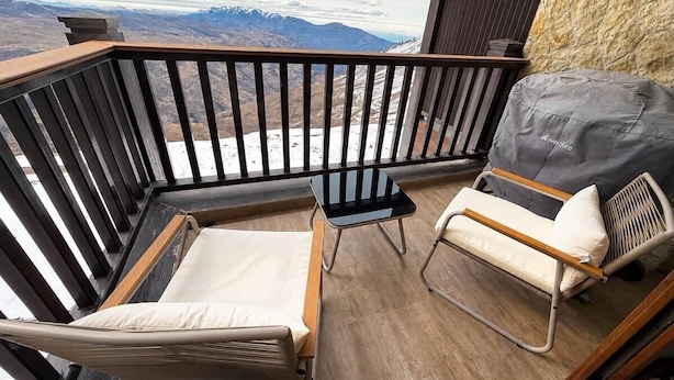A balcony with a wooden floor, two chairs, a small table, and a view of mountains. - kery’s sweet home in valle nevado (Lo Barnechea)