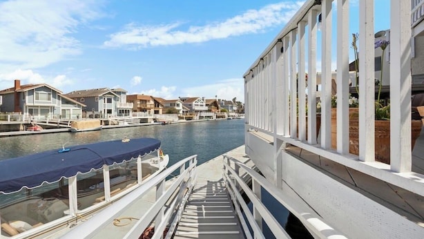 A waterfront property with a dock, a covered walkway, and residential buildings in the background.