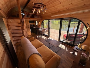 Ein Holzblockhaus-Interieur mit einer Couch, einem Esstisch und Seeblick durch große Fenster.