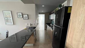 A modern kitchen with a black refrigerator, a wooden countertop, and a tiled floor. - Apartamento ejecutivo. Increible estancias largas (Santiago de Querétaro)