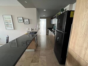 A modern kitchen with a black refrigerator, a wooden countertop, and a tiled floor. - Apartamento ejecutivo. Increible estancias largas (Santiago de Querétaro)