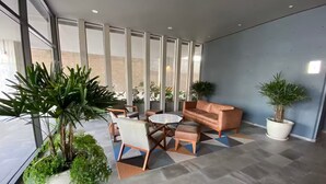 A modern interior with a seating area, large windows, and potted plants. - Apartamento ejecutivo. Increible estancias largas (Santiago de Querétaro)