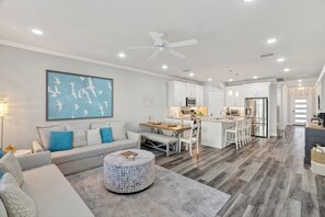 Ein modernes Wohnzimmer mit einer Couch, einem Hocker und einem Essbereich mit Tisch und Stühlen.