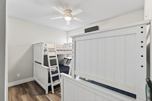 Ein Zimmer mit einem Etagenbett, einem Deckenventilator und einem weißen Kleiderschrank.