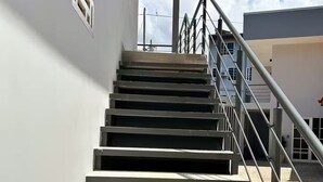 A set of outdoor stairs leading to a building entrance, with a metal handrail and a clear sky in the background. - Jaco beach apartment (Jacó)