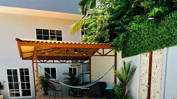 A swimming pool with a wooden deck area, a hammock, and potted plants. - Jaco beach apartment (Jacó)