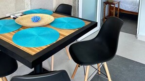 A room with a bed, a table with blue placemats, black chairs, and a stone wall. - Jaco beach apartment (Jacó)