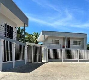 A modern building with a gated entrance, a covered walkway, and a clear sky. - Jaco beach apartment (Jacó)