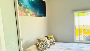 Ein Schlafzimmer mit einem Bett, einem Gemälde und einem Fenster.