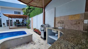 Ein Pool mit einer Steindekke, einem Grill und einer Spüle mit einer Steinrückwand.