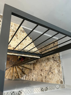 Eine Treppe mit Metallgeländer, gemusterten Bodenfliesen und einer dekorativen Bordüre.