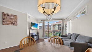 A spacious living area with a dining table, a sofa, and a TV. - Downtown Pool View 2 Bdrm 449 On The Lake (Kelowna)