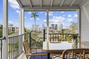 Un balcón con muebles de mimbre, una mesa y vistas a un paisaje urbano.