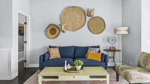 Ein Wohnzimmer mit einem blauen Sofa, einem Couchtisch und Wanddekoration.