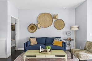Ein Wohnzimmer mit einem blauen Sofa, einem Couchtisch und Wanddekoration.