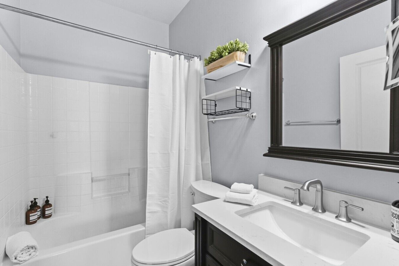 A modern bathroom with a shower, toilet, sink, and a large mirror.