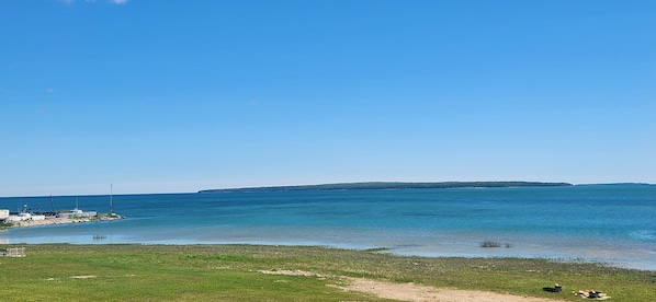 A coastal landscape with a clear sky, calm sea, and distant landmass.