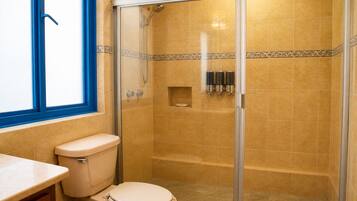 Ein Badezimmer mit Toilette, Duschkabine und Fenster.