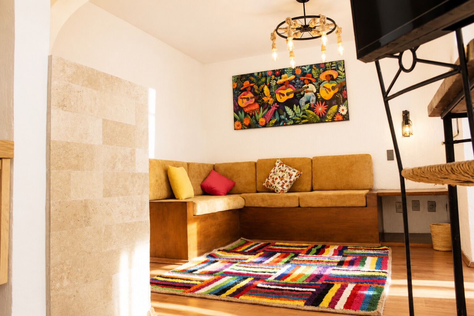 Una sala de estar con un sofá, alfombra colorida y un cuadro de músicos.