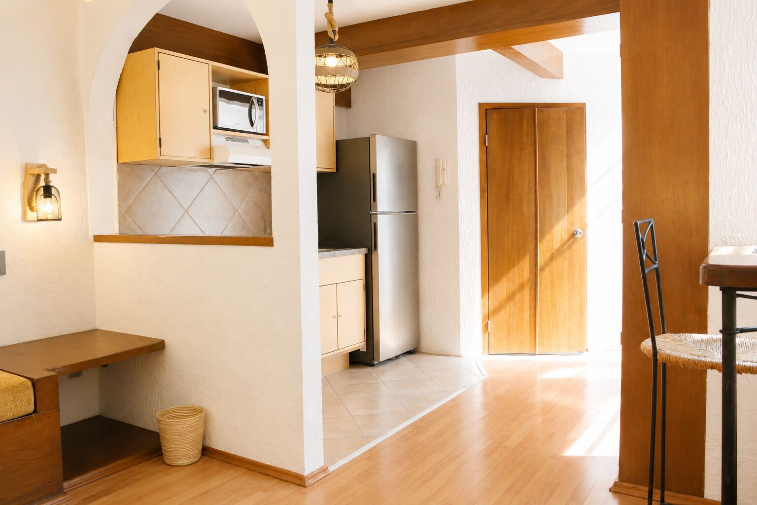 A kitchen with wooden cabinets, a refrigerator, and a hanging light fixture.