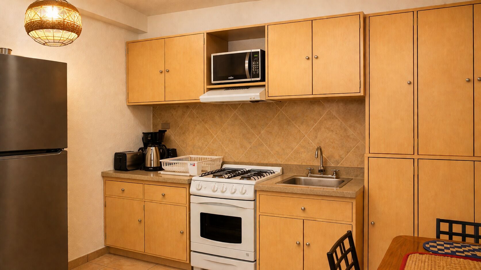 A compact kitchen with a refrigerator, stove, microwave, and a sink.