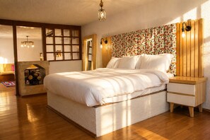 A bedroom with a large bed, wooden floor, a built-in fireplace, and a decorative wall panel. - El Rincon Mexicano Polanco by RUZ (Ciudad de México)