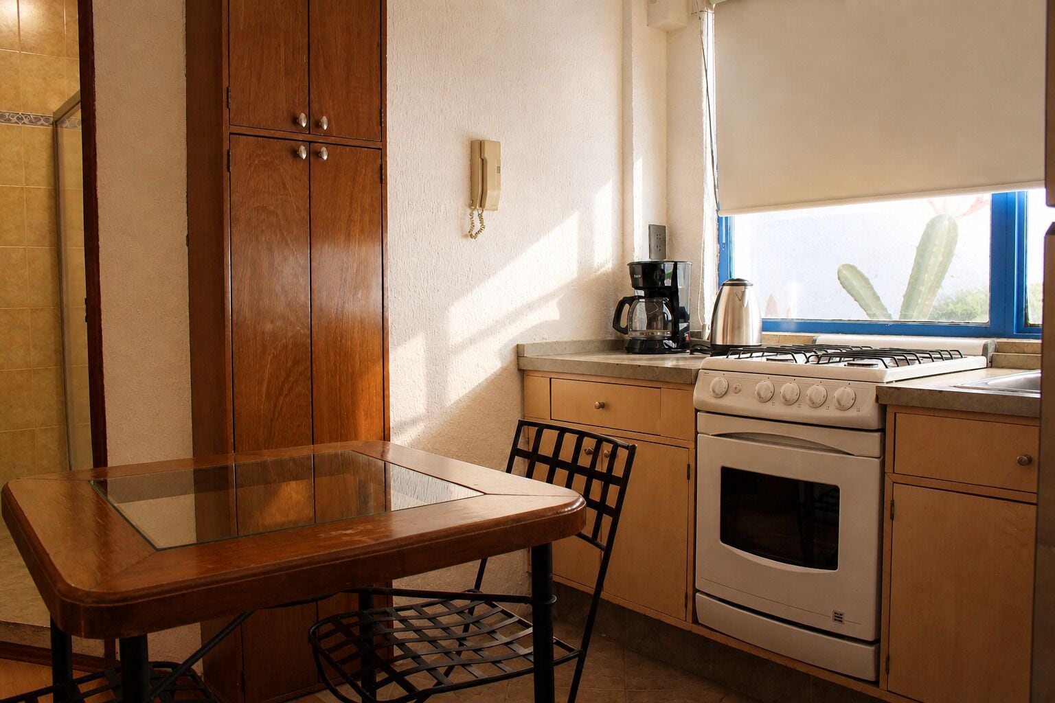 Una cucina con un tavolo di legno, sedie, un fornello e una macchina da caffè.