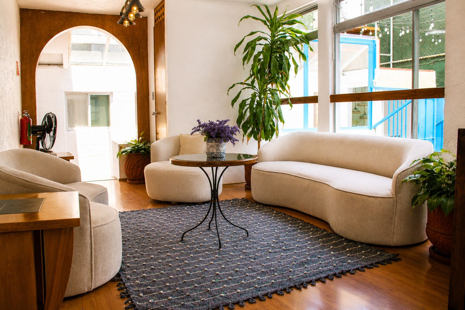 Una sala de estar con sofá, sillón y una mesa de centro con una planta.