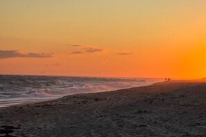 A beach with waves at sunset, a clear sky, and a few people in the distance. - Great sunsets on the beach in 3-bedroom Nantucket house with AC (Nantucket)