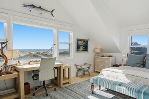 Une chambre avec un bureau, une chaise, un lit et une vue sur l’océan.