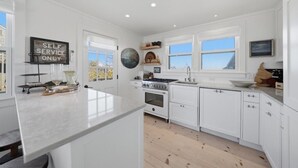 Una cocina moderna con armarios blancos, una isla central, una estufa y un lavabo.