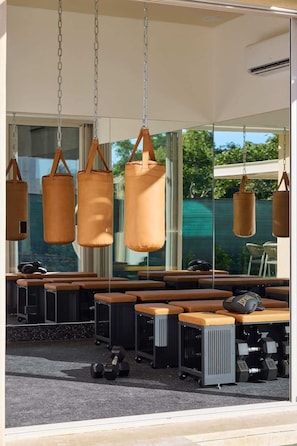 A gym with exercise equipment, benches, and hanging bags.
