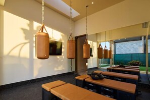 A modern room with hanging punching bags, a TV, and a view of the outdoors.